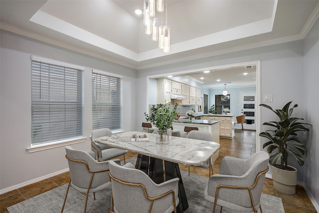 dining room with an inviting chandelier, dark tile patterned flooring, a tray ceiling, and ornamental molding