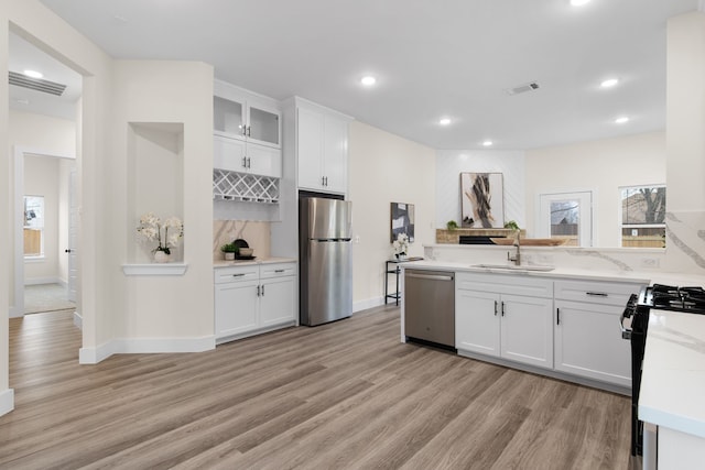 kitchen featuring sink, light wood-type flooring, light stone counters, white cabinetry, and stainless steel appliances