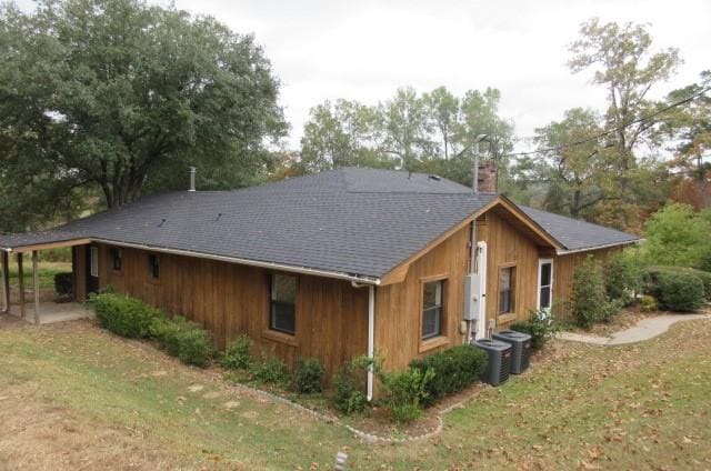 view of home's exterior with a carport, a yard, and central AC