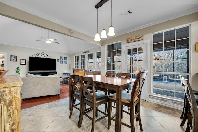 tiled dining area with ceiling fan and crown molding