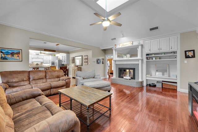 living room featuring high vaulted ceiling, crown molding, a brick fireplace, ceiling fan, and wood-type flooring