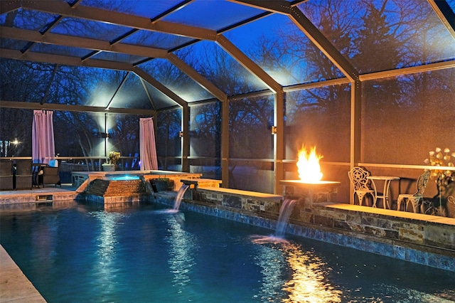 view of swimming pool featuring an in ground hot tub, pool water feature, and a lanai