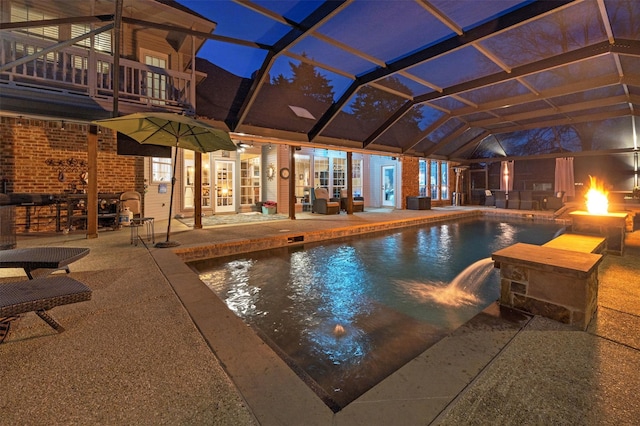 view of pool with pool water feature, glass enclosure, and a patio area