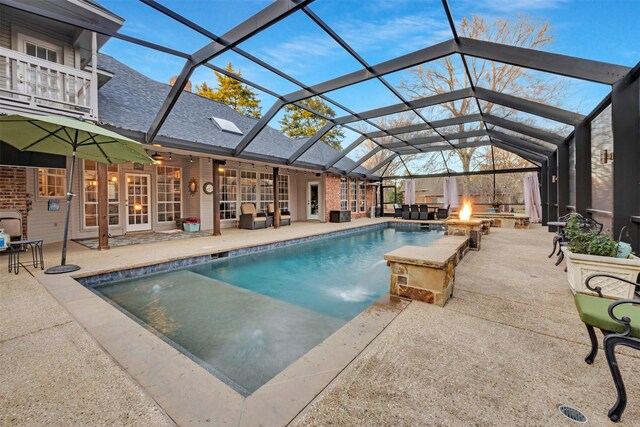 view of swimming pool featuring glass enclosure, an outdoor fire pit, a patio area, and ceiling fan