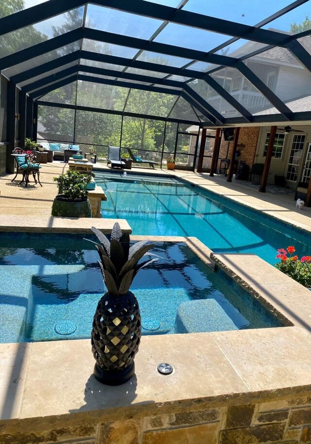 view of pool with glass enclosure and a patio