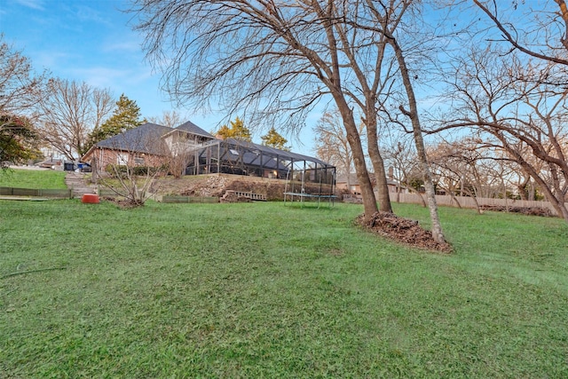 view of yard featuring glass enclosure and a trampoline