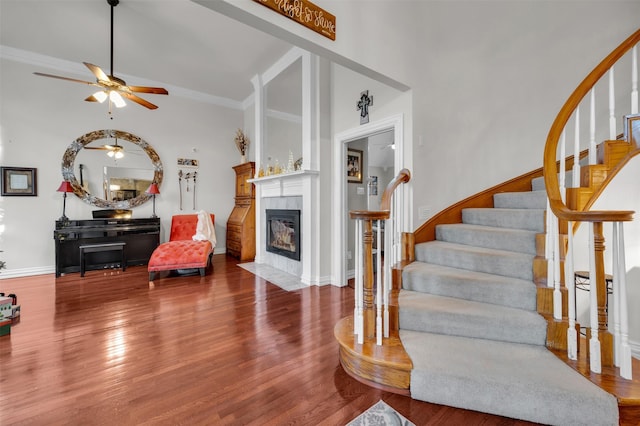 living room featuring crown molding, ceiling fan, a fireplace, and wood-type flooring