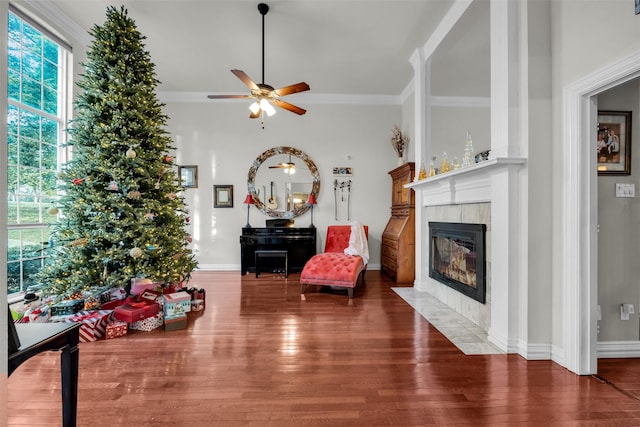 living area featuring a tile fireplace, dark hardwood / wood-style flooring, ceiling fan, and ornamental molding