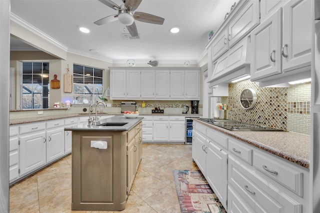 kitchen with a center island with sink, white cabinets, backsplash, and beverage cooler