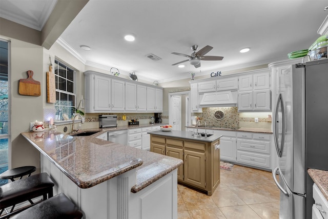 kitchen with appliances with stainless steel finishes, ceiling fan, sink, a center island, and white cabinetry