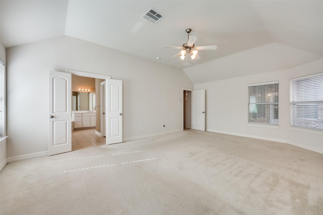 unfurnished bedroom featuring ceiling fan, ensuite bathroom, lofted ceiling, and light carpet