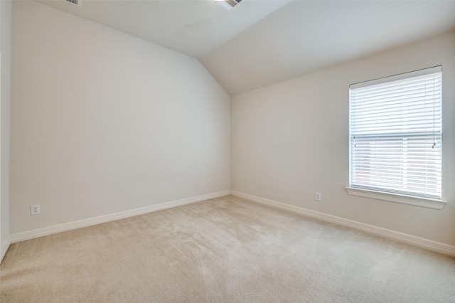 spare room featuring light colored carpet, plenty of natural light, and lofted ceiling