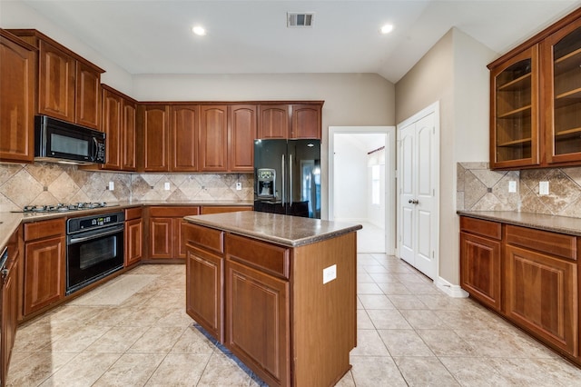 kitchen featuring backsplash, dark stone counters, light tile patterned flooring, a kitchen island, and black appliances