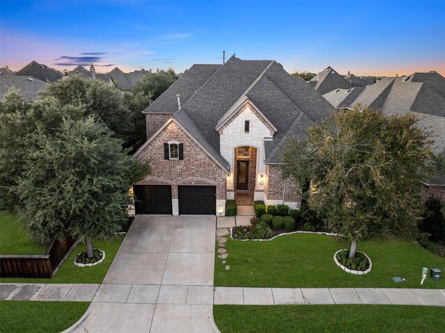 french country home with a yard and a garage