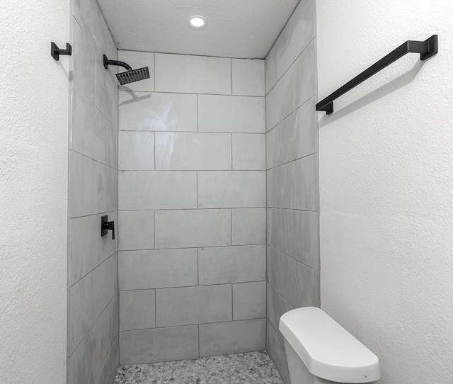 bathroom featuring a tile shower and toilet