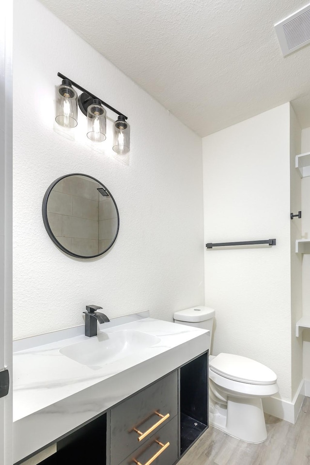 bathroom with vanity, a textured ceiling, hardwood / wood-style flooring, and toilet