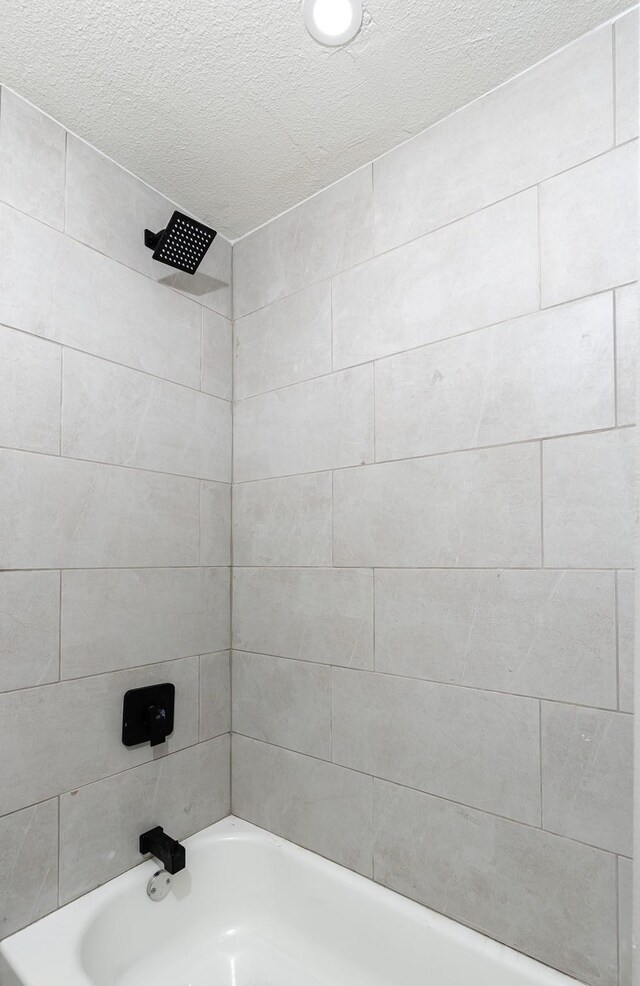 bathroom featuring tiled shower / bath combo and a textured ceiling