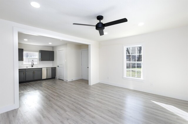 unfurnished living room featuring light wood-type flooring, ceiling fan, and sink