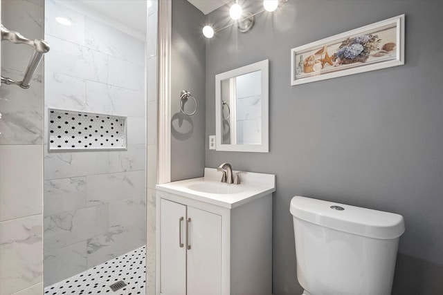 bathroom with toilet, vanity, and tiled shower