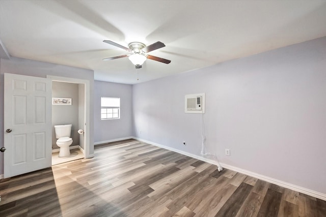 unfurnished bedroom featuring dark wood-type flooring, a wall unit AC, and ceiling fan