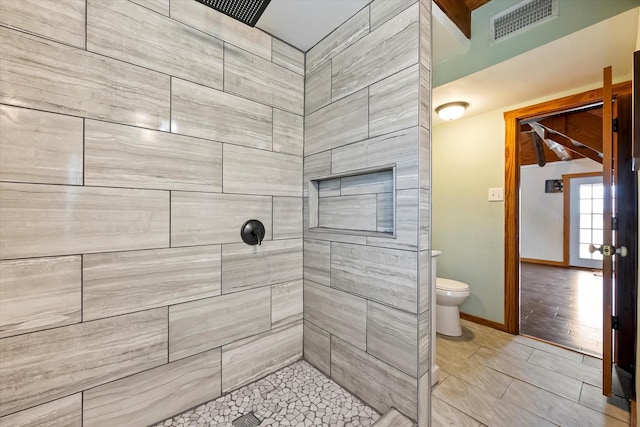 bathroom featuring a tile shower, tile patterned floors, and toilet