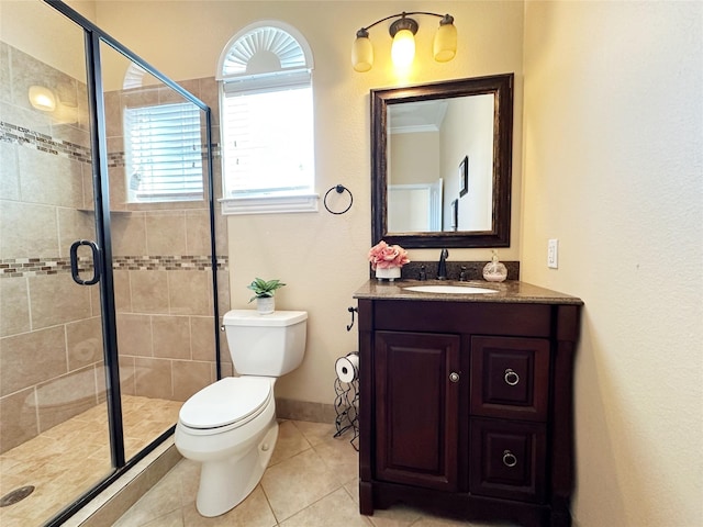 bathroom with tile patterned flooring, vanity, toilet, and a shower with door