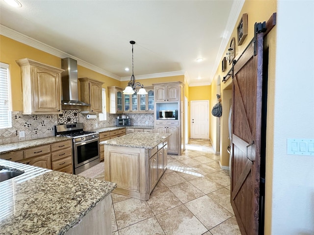 kitchen with decorative backsplash, stainless steel appliances, wall chimney range hood, a barn door, and a center island