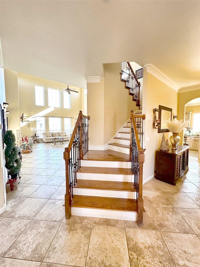 staircase featuring ceiling fan, tile patterned flooring, and ornamental molding