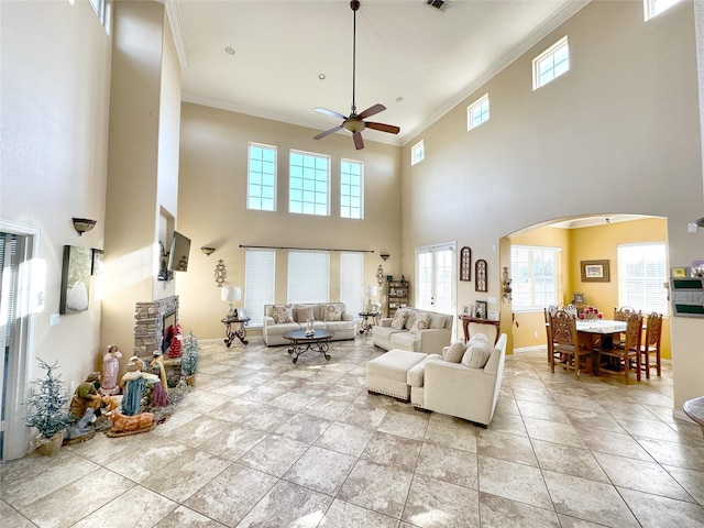 living room featuring ceiling fan, ornamental molding, a fireplace, and light tile patterned floors