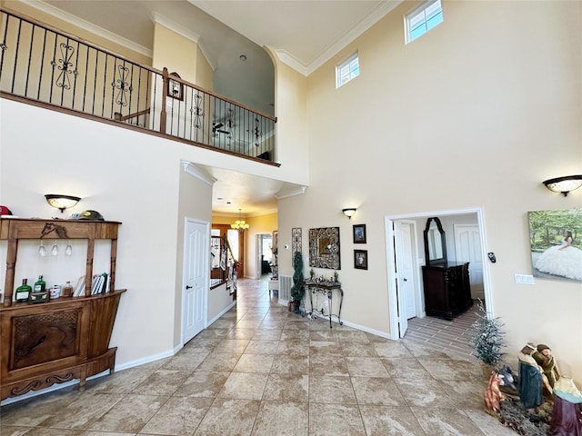 tiled foyer entrance with a chandelier, a towering ceiling, and crown molding