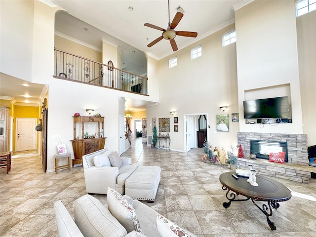 living room featuring ceiling fan, a stone fireplace, a towering ceiling, and ornamental molding