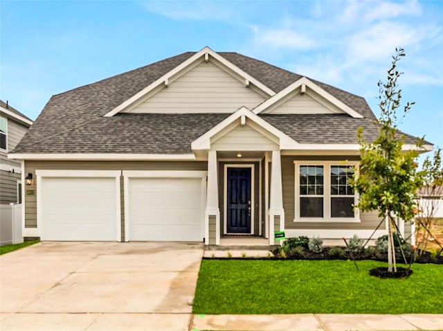 view of front of property with a garage, driveway, a shingled roof, fence, and a front yard