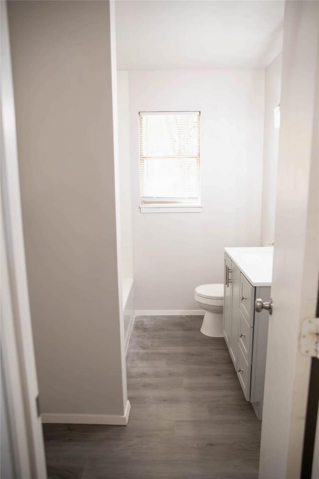 bathroom featuring vanity, wood-type flooring, a washtub, and toilet