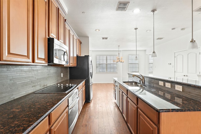 kitchen with decorative backsplash, sink, stainless steel appliances, and hanging light fixtures