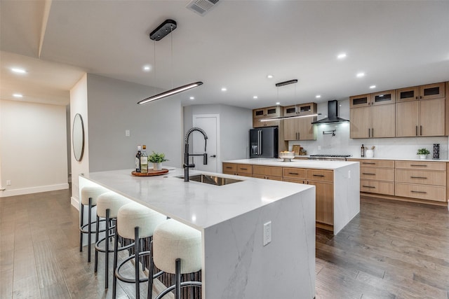 kitchen with black fridge with ice dispenser, decorative light fixtures, a large island, and sink