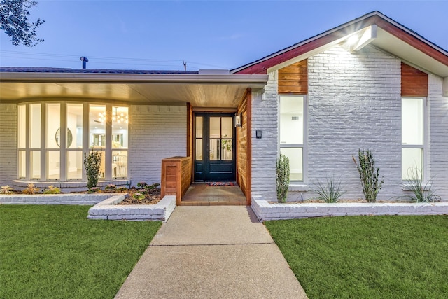 view of exterior entry featuring a lawn