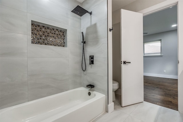 bathroom with tile patterned floors, tiled shower / bath combo, and toilet