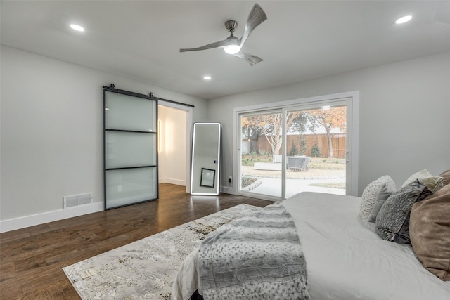 bedroom featuring ceiling fan, a barn door, dark hardwood / wood-style floors, and access to outside