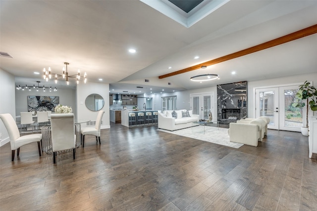 living room featuring beamed ceiling, french doors, a chandelier, and dark wood-type flooring