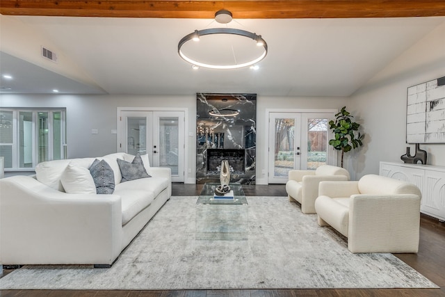 living room featuring a premium fireplace, french doors, dark wood-type flooring, and lofted ceiling