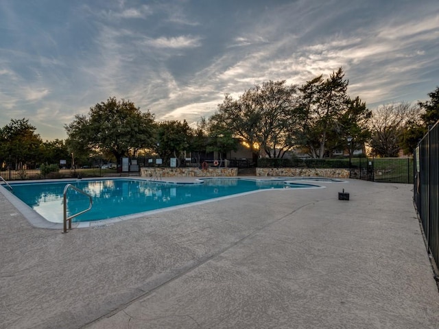 pool at dusk featuring a patio area