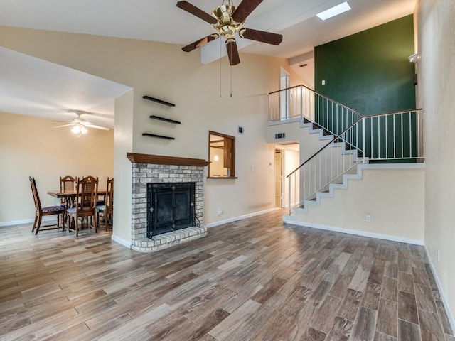 living room with a fireplace, wood-type flooring, high vaulted ceiling, and ceiling fan