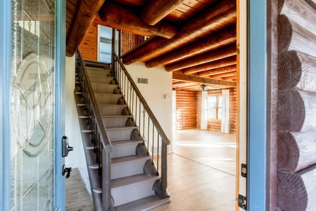 stairway with rustic walls, wood ceiling, hardwood / wood-style flooring, and beam ceiling