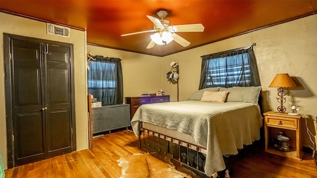 bedroom featuring ceiling fan, crown molding, and hardwood / wood-style flooring