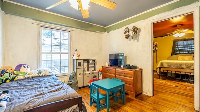 bedroom with wood-type flooring, ceiling fan, and ornamental molding