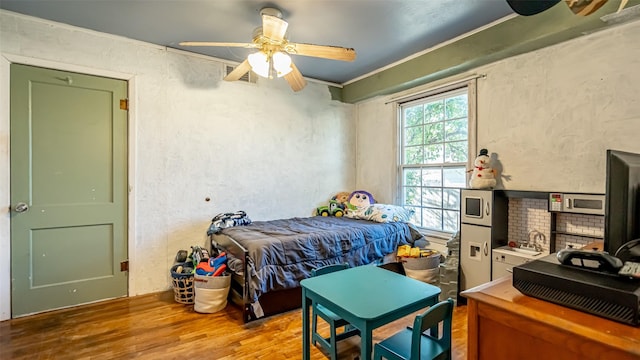 bedroom with ceiling fan, crown molding, wood-type flooring, and sink