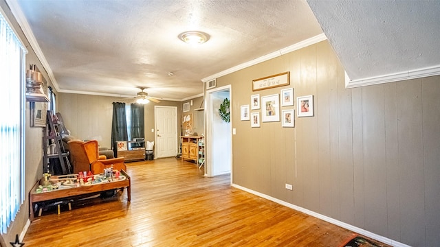 living area with crown molding, ceiling fan, a textured ceiling, and hardwood / wood-style flooring