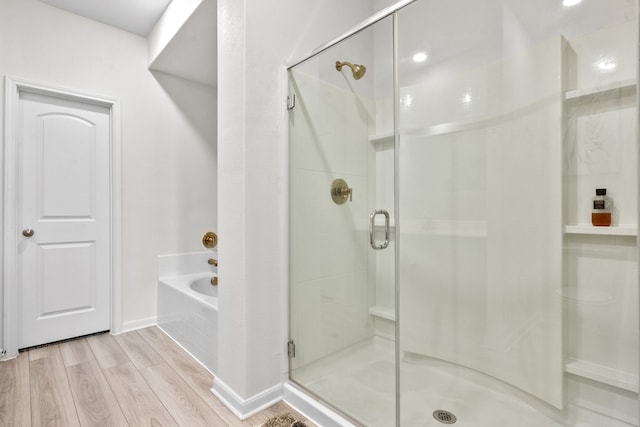 bathroom with hardwood / wood-style flooring and independent shower and bath