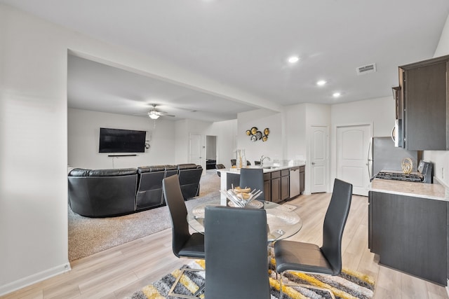 dining area with ceiling fan, sink, and light hardwood / wood-style flooring