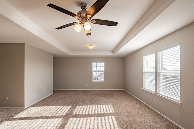 empty room with a tray ceiling, ceiling fan, and carpet flooring